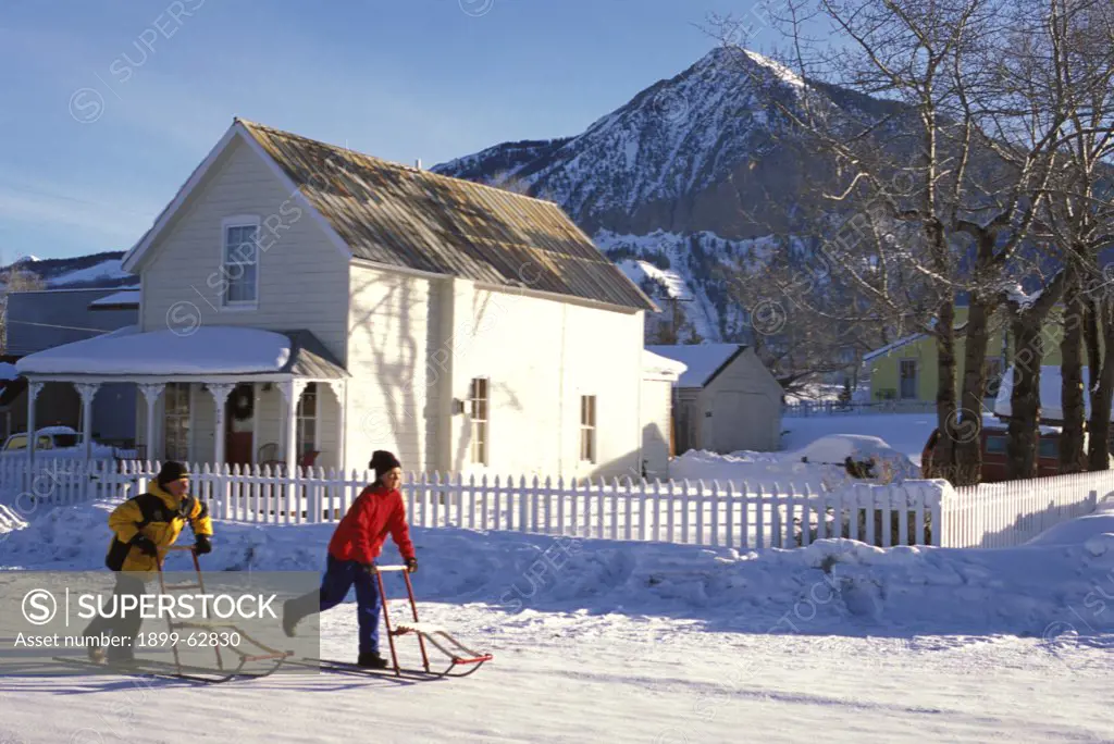 Colorado, Crested Butte. Children Riding Kicksleds Down The Street.