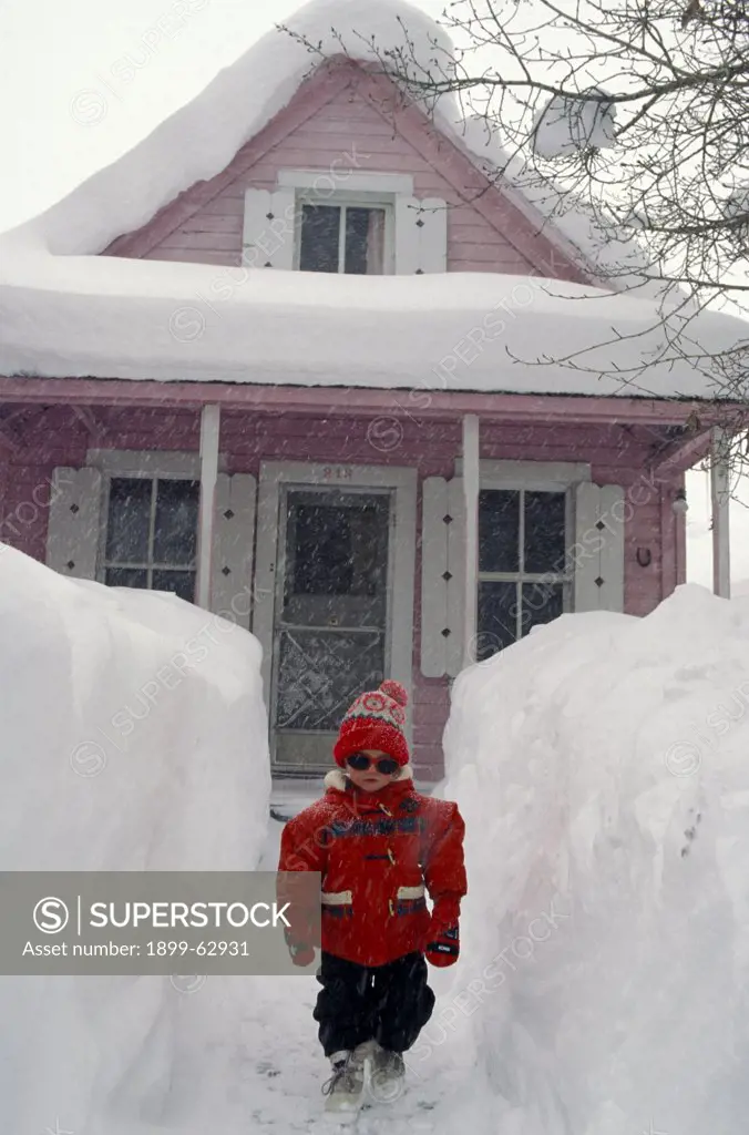 Colorado. Little Girl On Pathway In Front Of House, Surrounded By Mounds Of Snow