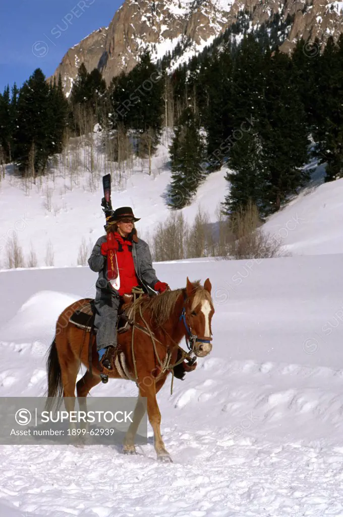 Colorado. Woman Riding Horse In Snow, Carrying Skis