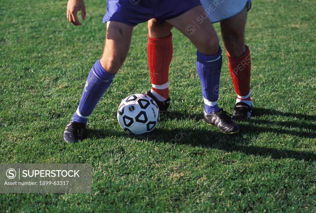 Soccer Ball And Legs Of Two Opposing Players