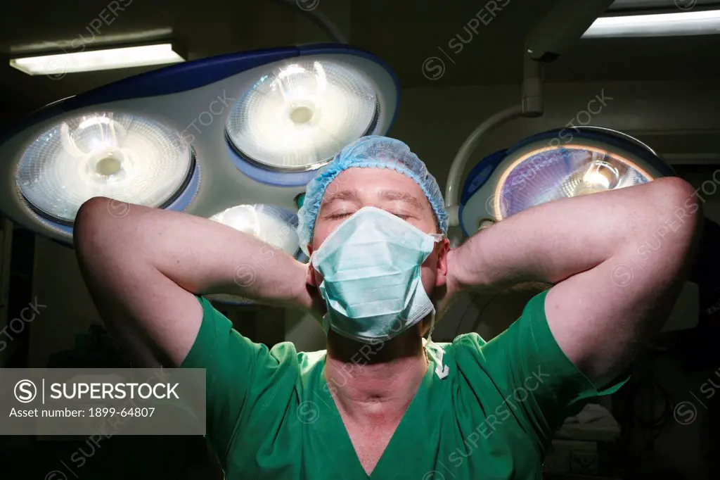 Surgeon standing with eyes closed and hands behind head