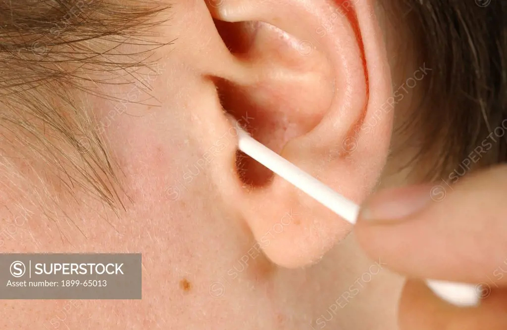 Man cleaning his ear canal with cotton bud, close-up