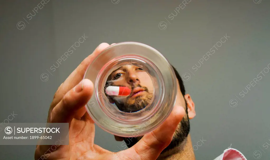 Man looking at pill at bottom of glass