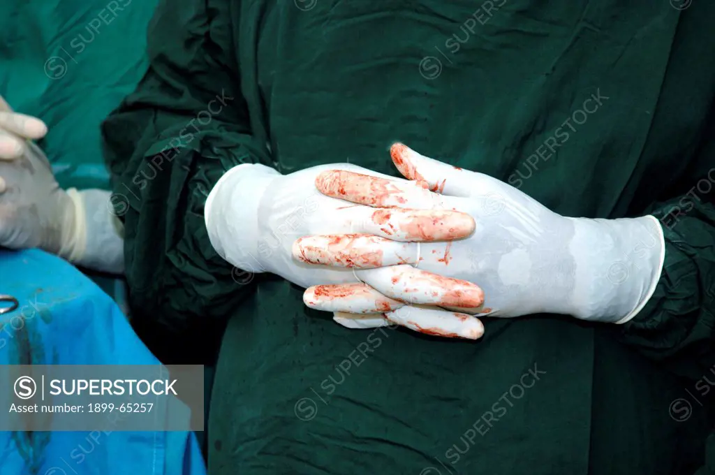Blood stained gloved hands, Clasped together. Sudan, Africa.