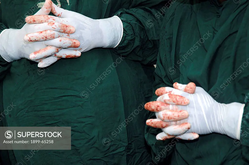 Blood stained gloved hands, Clasped together. Sudan, Africa.