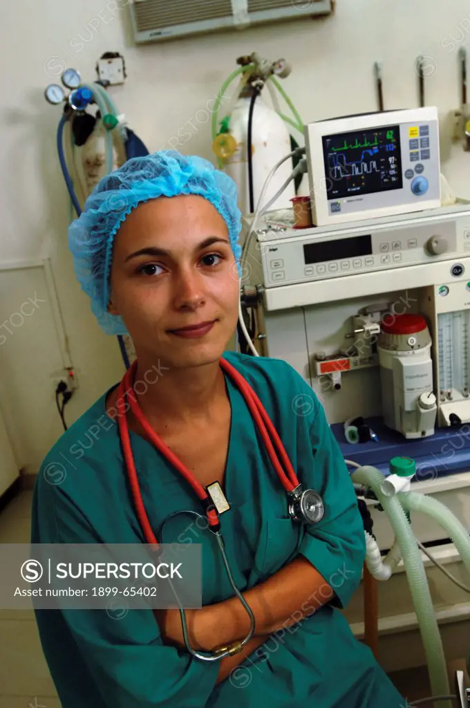 Female nurse wearing green surgical gown and cap sitting