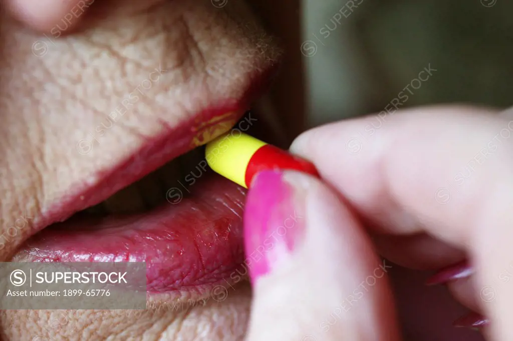 Elderly woman placing capsule into her mouth