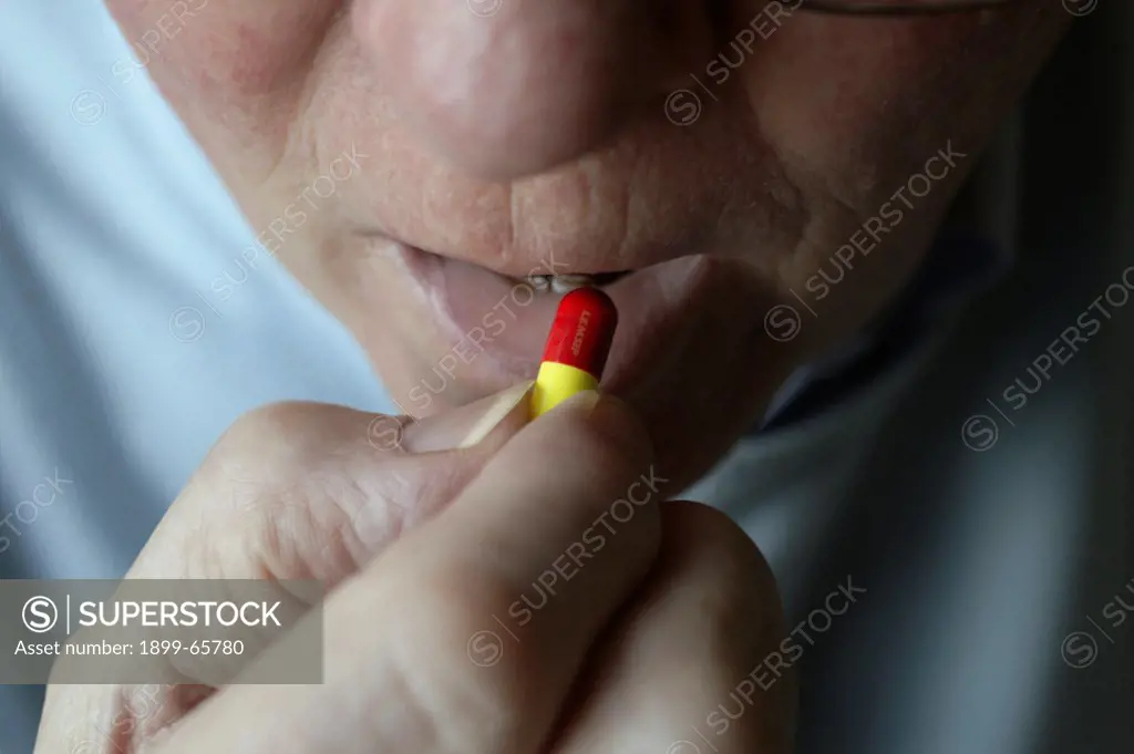 Elderly man placing capsule into his mouth