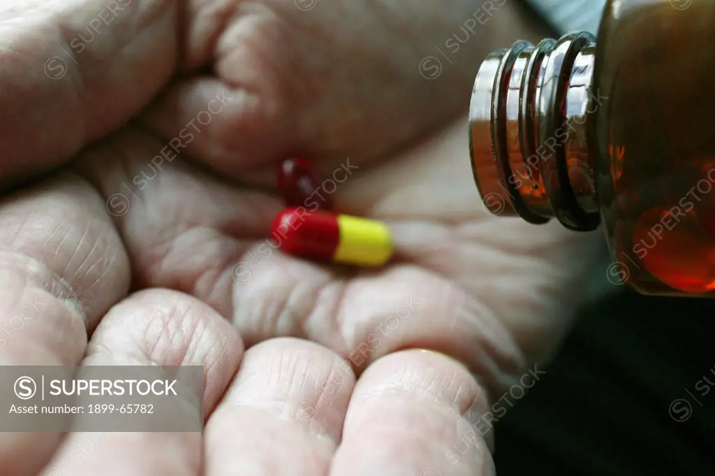 Elderly man pouring medication tablets on hand