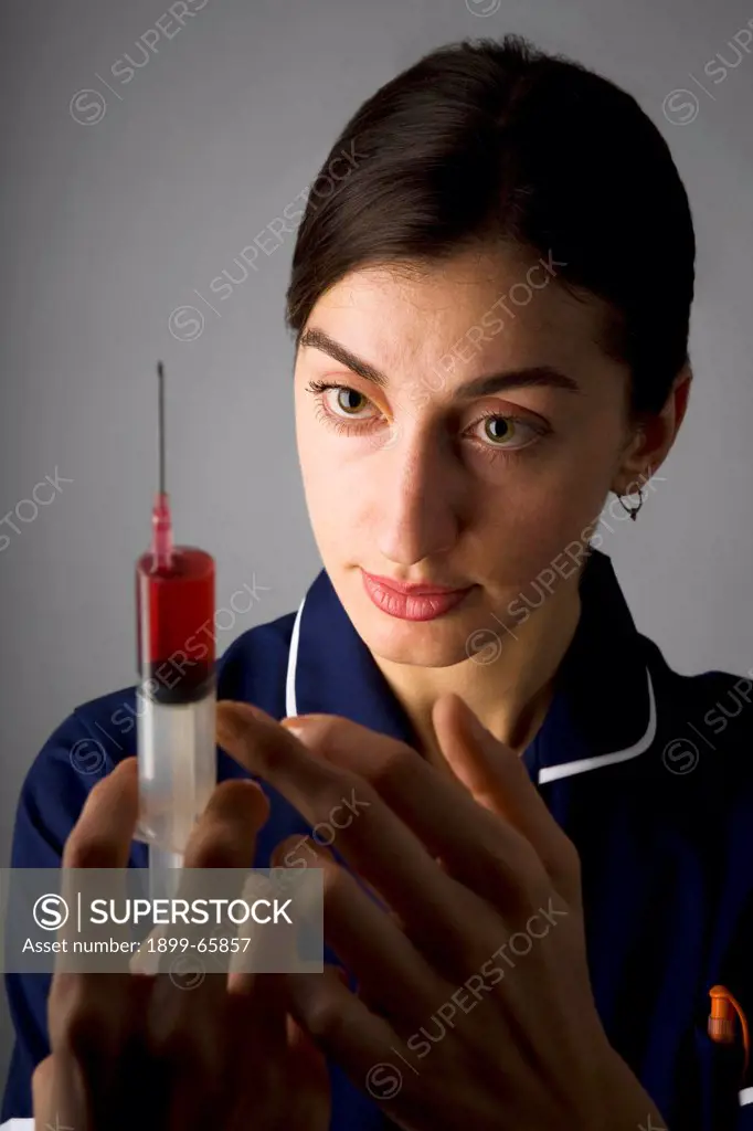 Nurse holding syringe containing red solution
