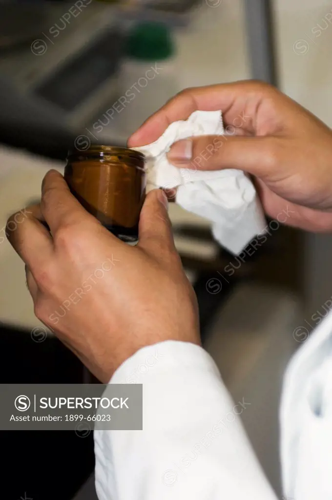 Hospital pharmacist filling jar with newly prepared
