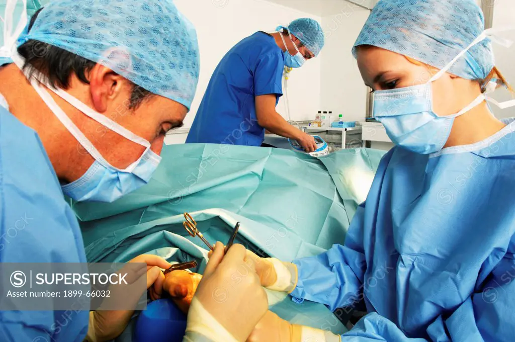 Surgeon, nurse and anesthetist operating on patient with hand disorder