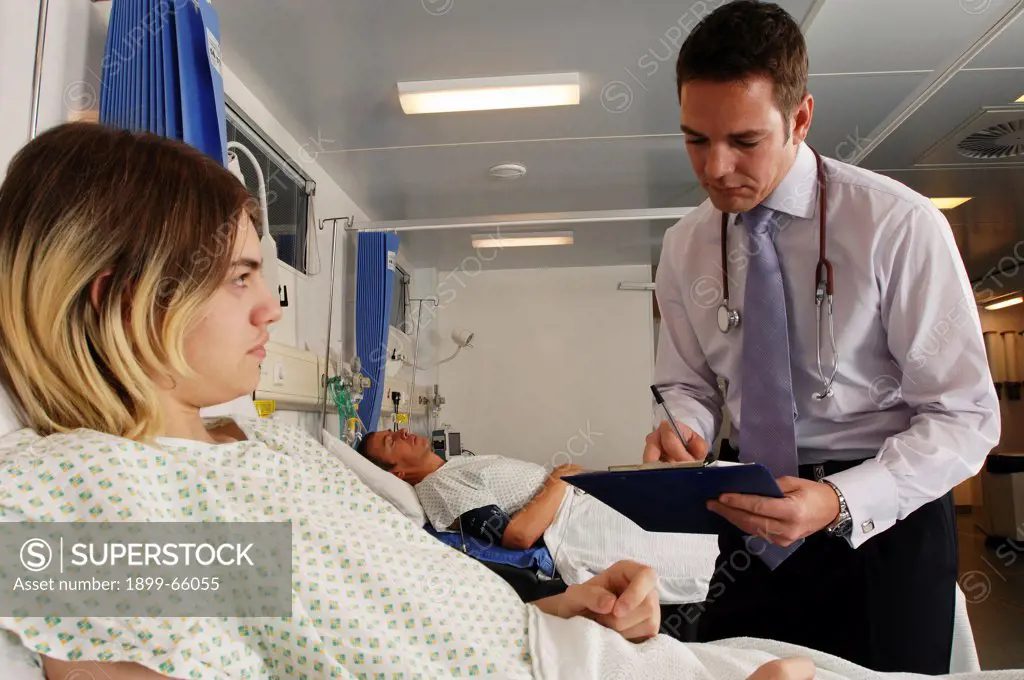 Doctor in discussion with patient, making notes at bedside