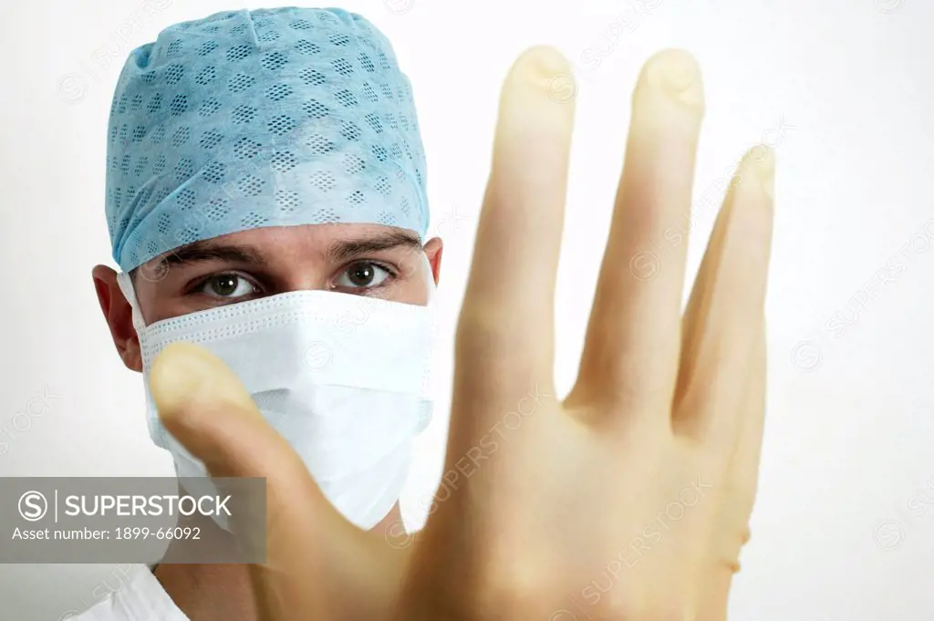 Young male doctor putting on disposable latex gloves