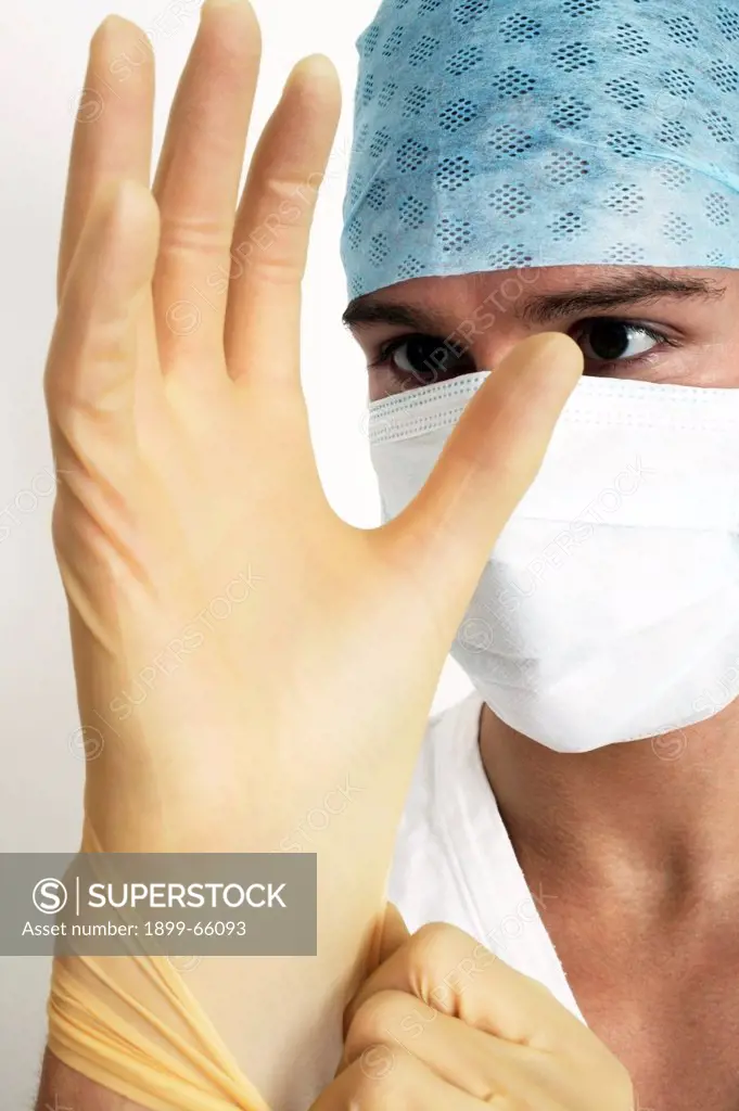 Young male doctor putting on disposable latex gloves