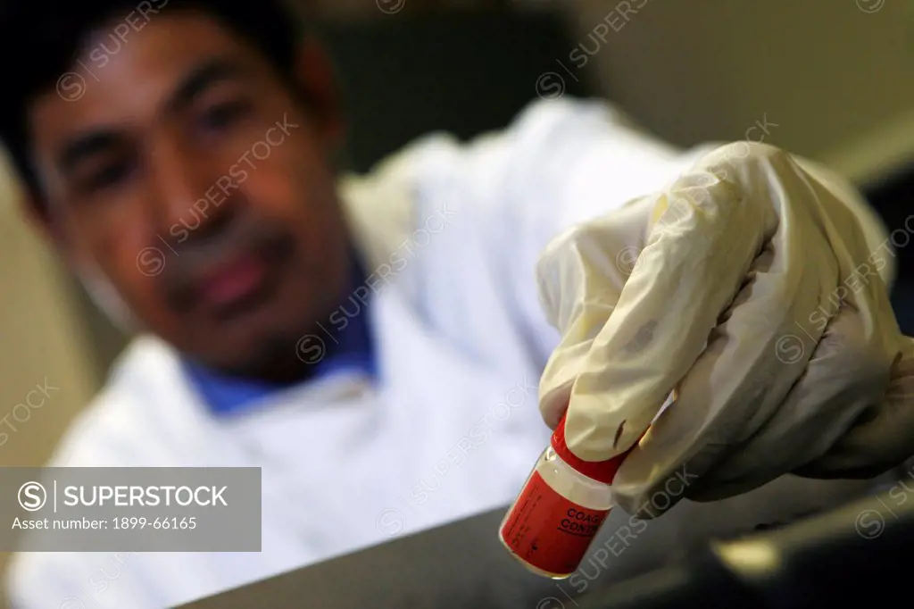 Pathologist examining small glass bottled specimen
