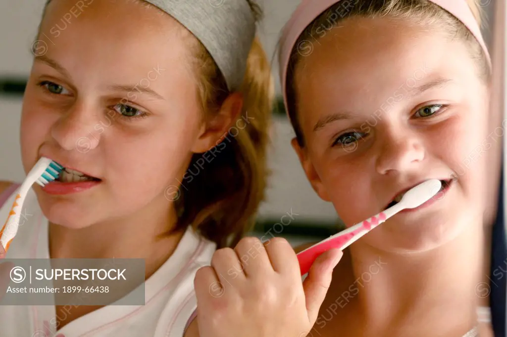 Two girls brushing teeth