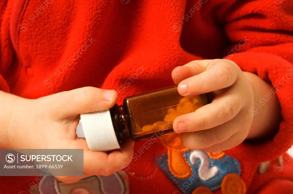 Close-up of baby boy trying to open medicine bottle,