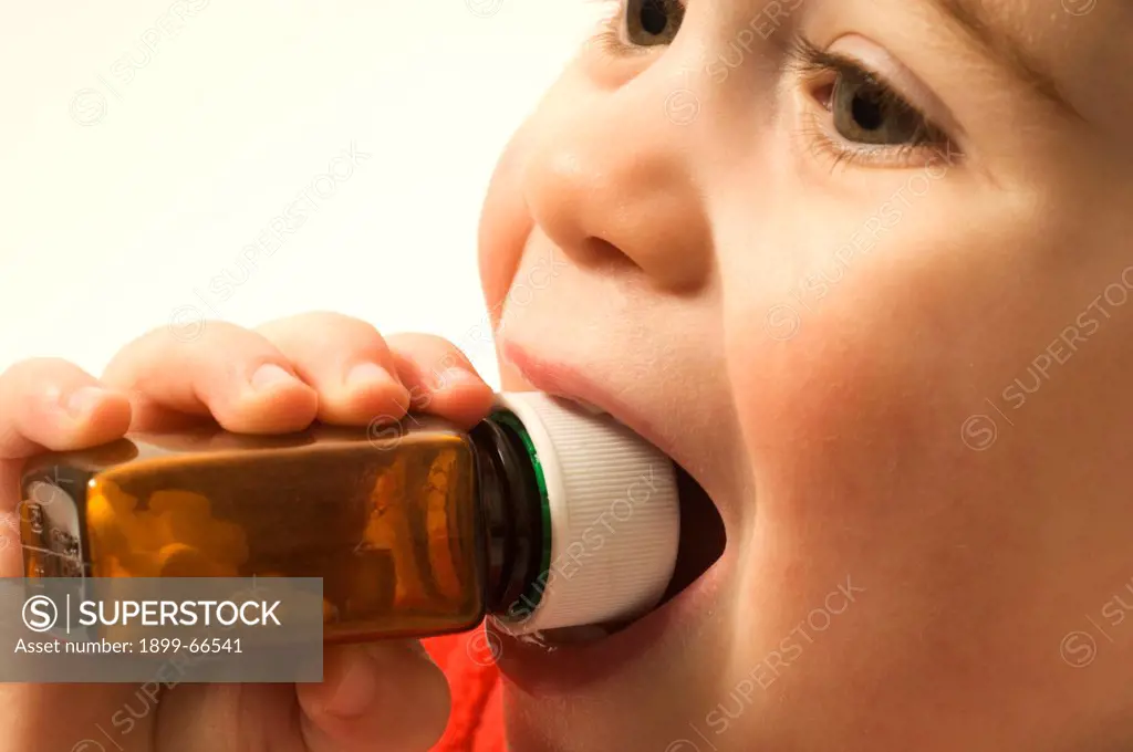 Close-up of baby boy with medicine bottle in mouth