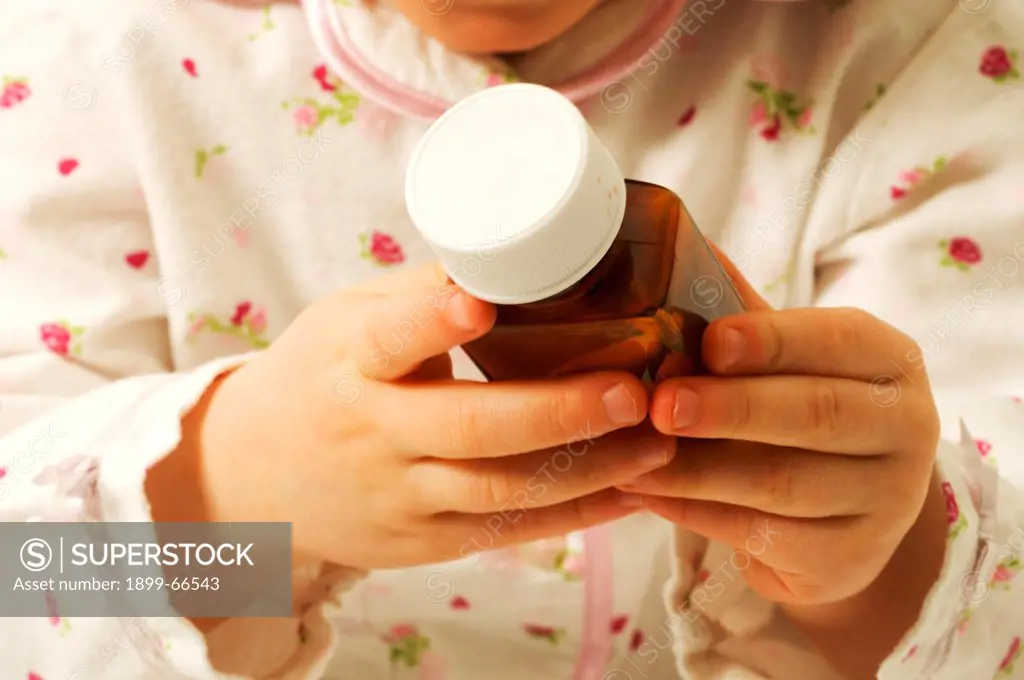 Close-up of baby girl trying to open medicine bottle,