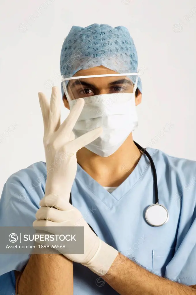 Portrait of surgeon putting on disposable latex gloves