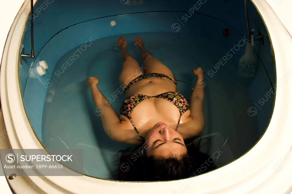 Young woman laying in relaxing flotation tank filled