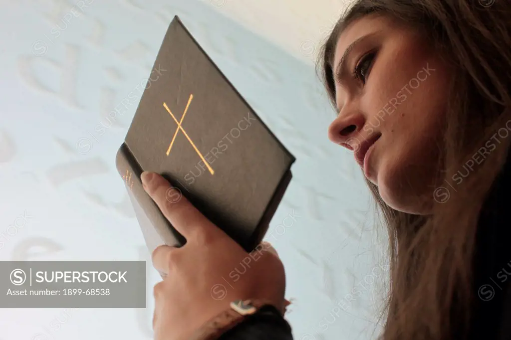 Young woman reading the bible in a church.