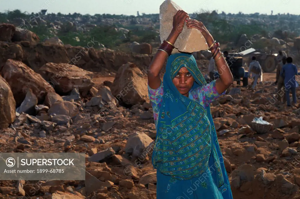 Quarry worker carrying a boulder on her head