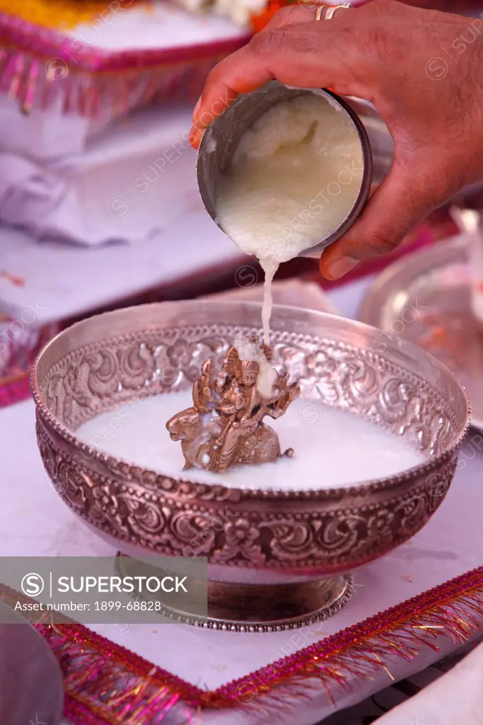 Puja in a Hindu temple : bathing of a statue of goddess Durga with semolina
