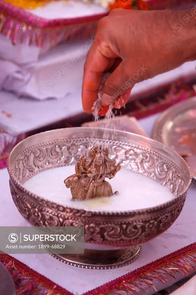 Puja in a Hindu temple : rice offering to a statue of goddess Durga bathed in curd