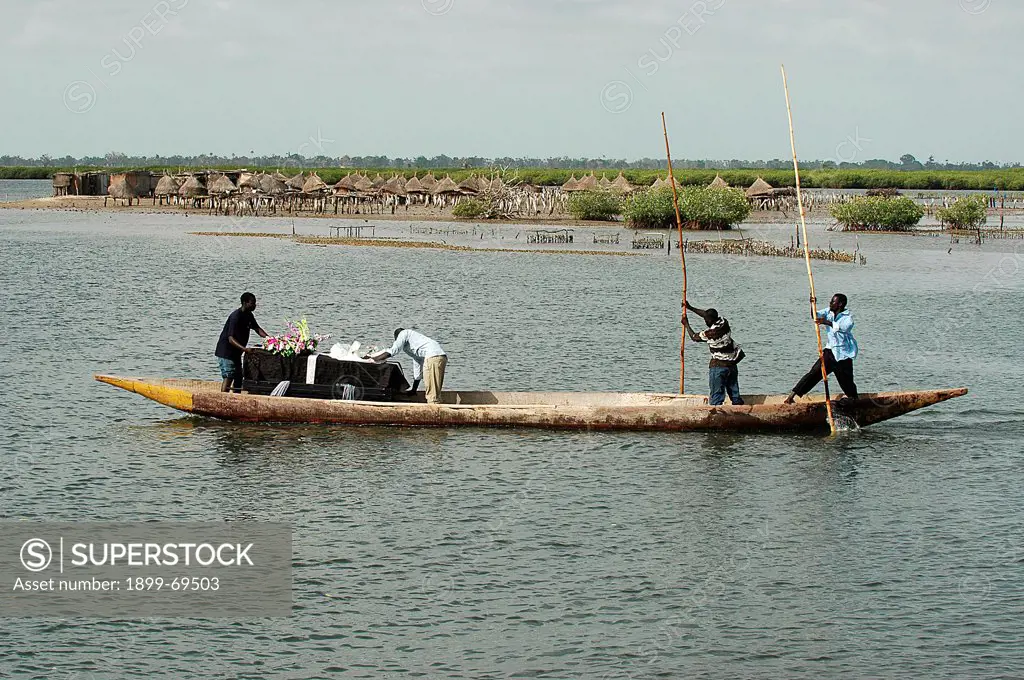 African funeral Coffin taken to an island cemetery by boat
