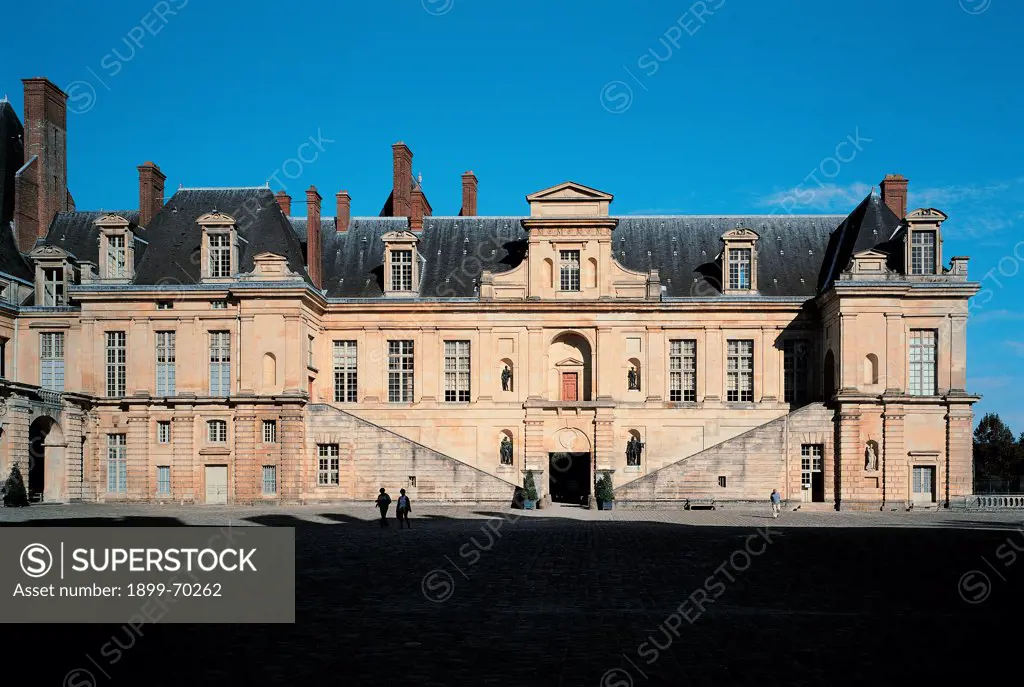 France, Fontainebleau, Palace of Fontainebleau. Detail. Fontainebleau 'Cour de la Fontaine' court and 'aile Charles IX' wing, realized in ashlar technique, with flight of steps. Windows and chimneypots on the roof stand against the sky.