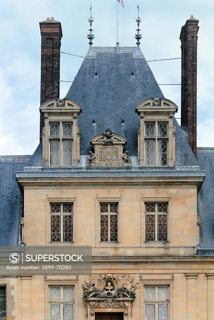 France, Fontainebleau, Palace of Fontainebleau. Detail. Fontainebleau 'cour du Cheval blanc' court. Eastern facade, detail of the second floor. Roof with slopes. Lucarne, chimneypot and dormer window are main details. The portal can be glimpsed.