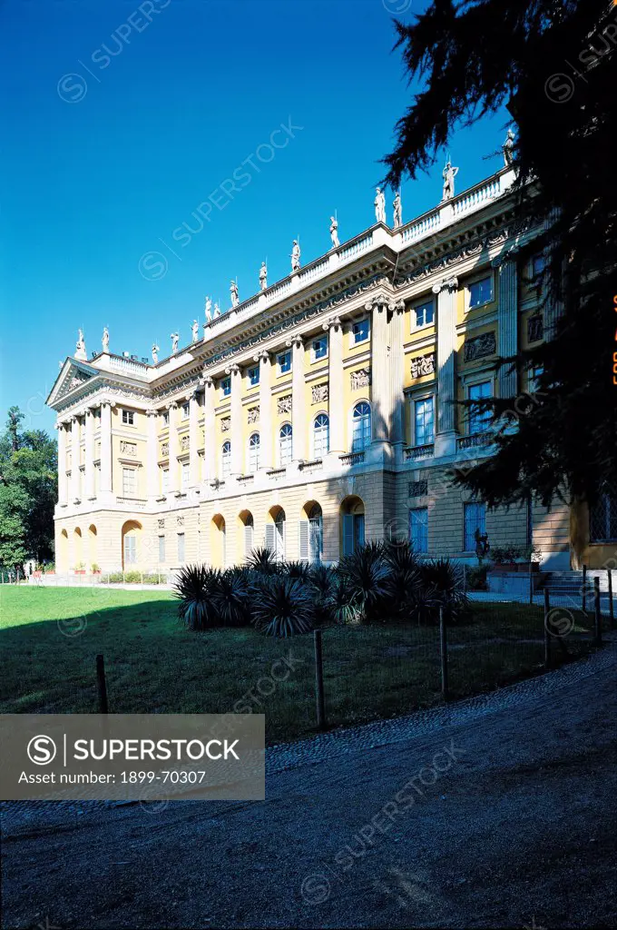 Italy, Lombardy, Milan, via Palestro. Detail. A front view of the palace of the villa that faces a large meadow. The frontage shows balustrades, pilasters, statues, a tympanum contained by cornice, a frieze and reliefs.