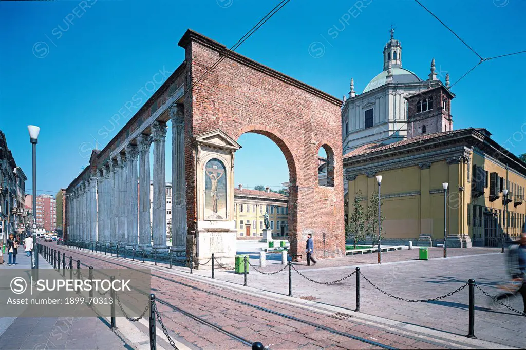 Italy, Lombardy, Milan, Porta Ticinese main street. Detail. External view of the Basilica, whose dome is visible on the right, with an arch and the columns that run along Porta Ticinese main street.
