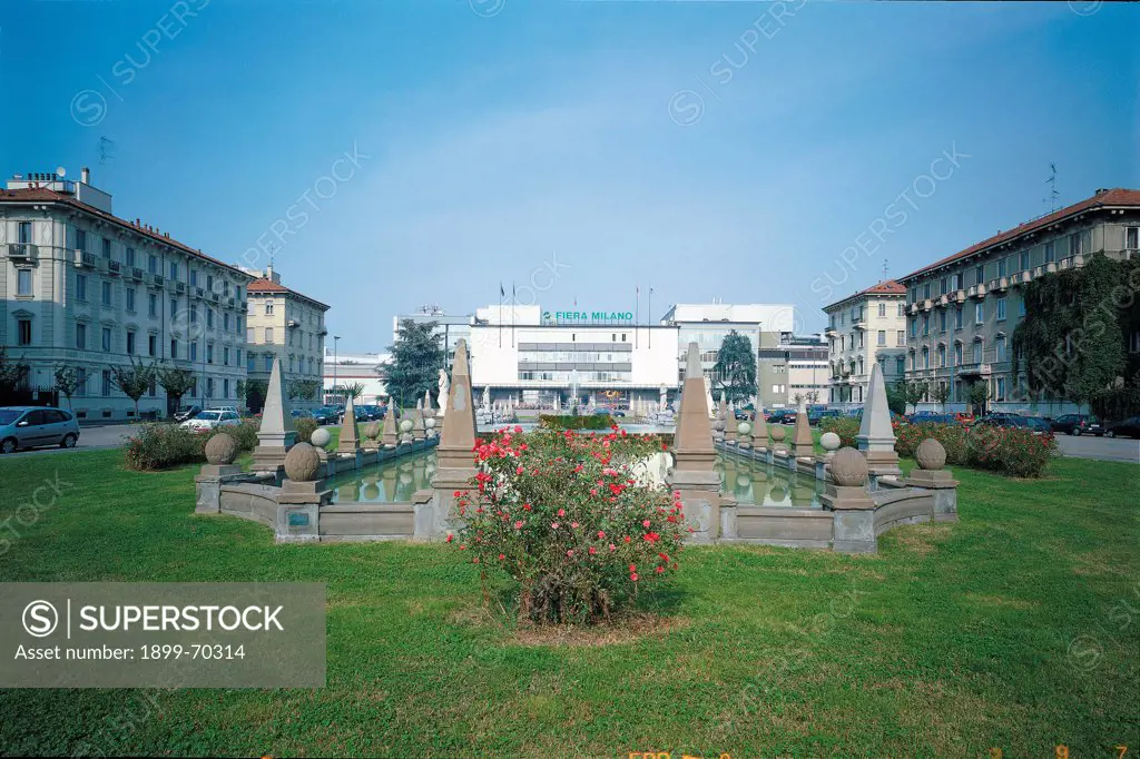 Italy, Lombardy, Milan. Whole artwork view. A view of the square, with its fountain and in the background the entrance of Fiera Milano.