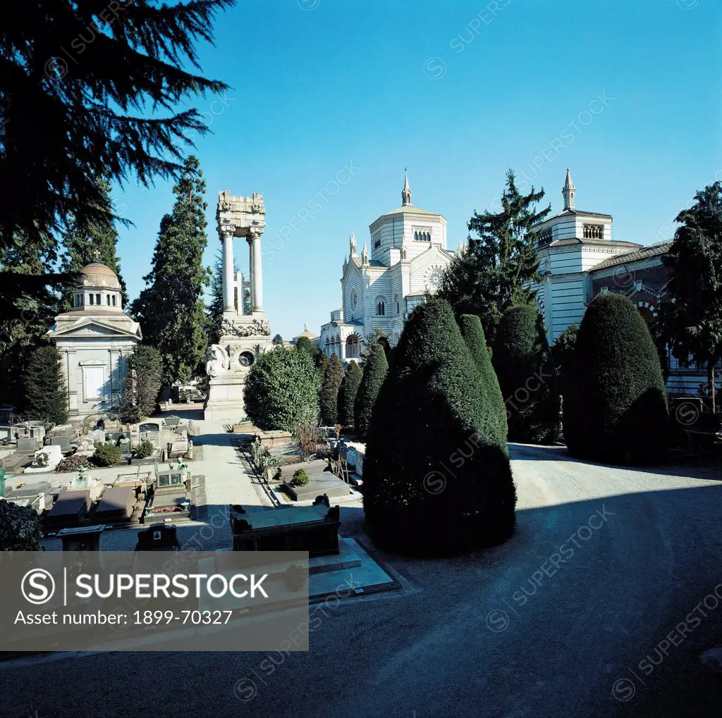 Italy, Lombardy, Milan, Memorial Cemetery. Detail. A view of the interior of the cemetery, with memorial stones, tombs, plants, evergreen plants and trees.