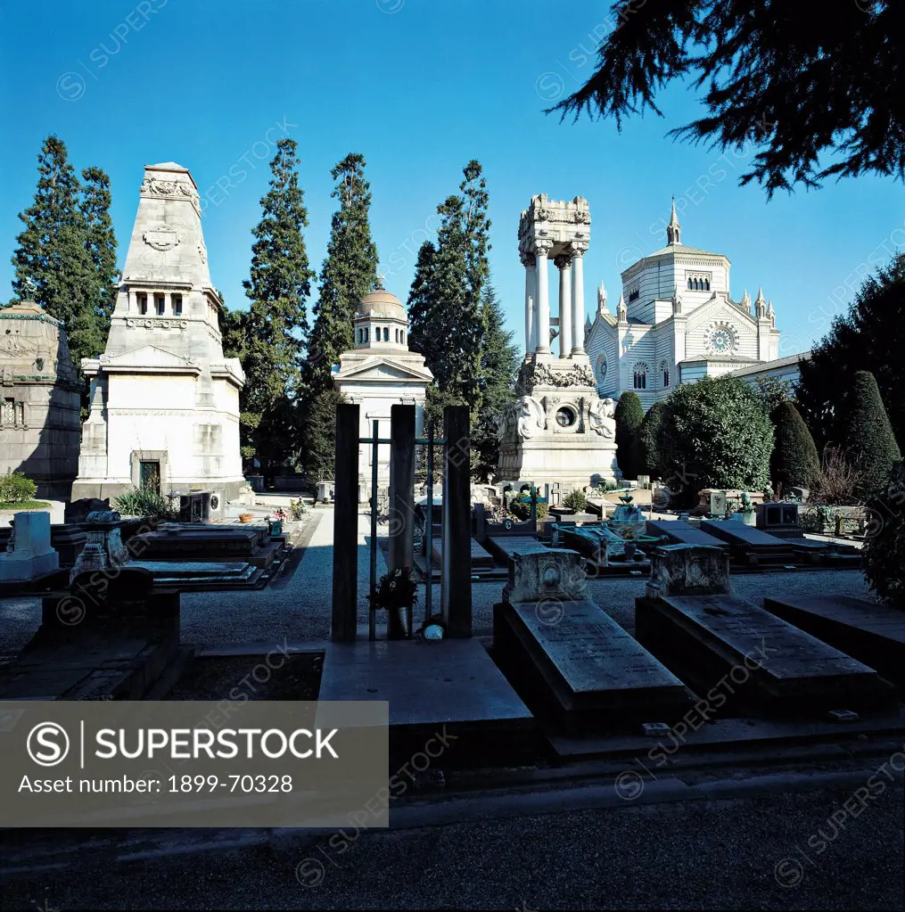 Italy, Lombardy, Milan, Memorial Cemetery. Detail. A view of the interior of the cemetery, with memorial stones, tombs, plants, evergreen plants and trees.