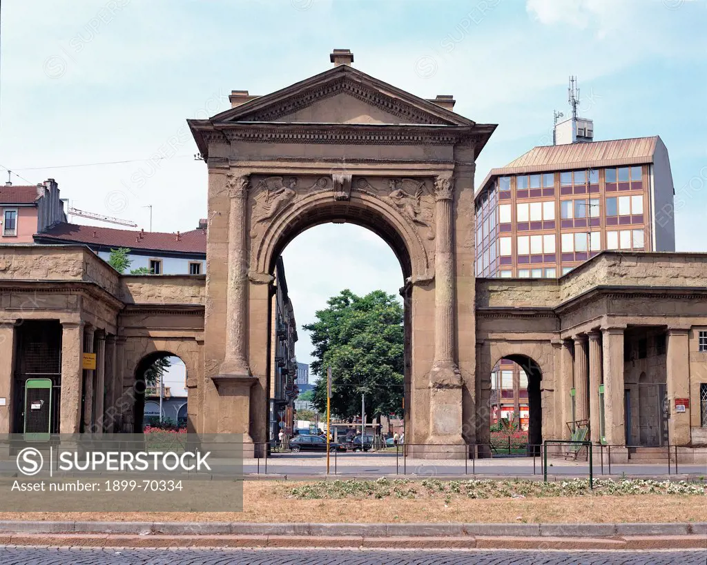 Italy, Lombardy, Milan, Principessa Clotilde square. Whole artwork view. Frontal view of arch with barrel vault and columns, capitals, architrave. Beside the gate, made with sandstone, there are colonnades that used to be customs.