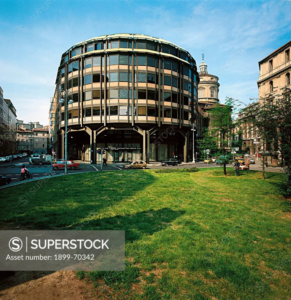 Italy, Lombardy, Milan, Piazza Meda. View of the office building in piazza Meda, in Milan, from the opposite gardens. The outside of the circular structure is made of glass and steel, with pillars in the ground floor portico.