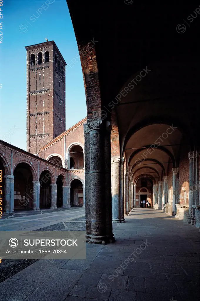 Italy, Lombardy, Milan, Basilica of St. Ambrose. View from the entrance to the façade, showing the arcades, the columns, the portico and the bell tower in the background.