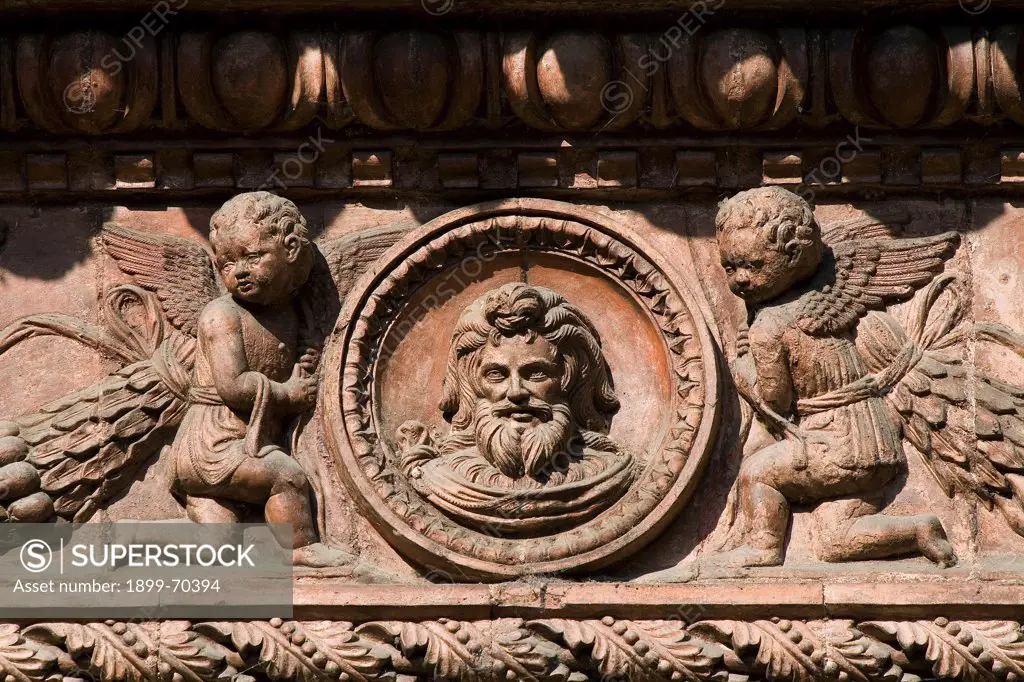 Italy, Lombardy, Pavia, Carthusian monastery. Detail. Terracotta frieze in the small cloister. The decoration depicts two winged putti on the two sides of a tondo with a man's face in it.