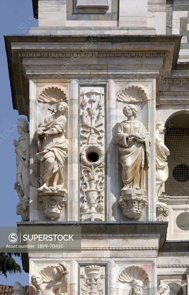 Italy, Lombardy, Pavia, Carthusian monastery. Detail. Detail of the monastery front, showing a buttress with polychrome marble inlays and bas-reliefs. On the front side of the buttress are two niches with the statues of Saint Cecily and Saint Agatha. Above it, a tondo decorated with a human bust.