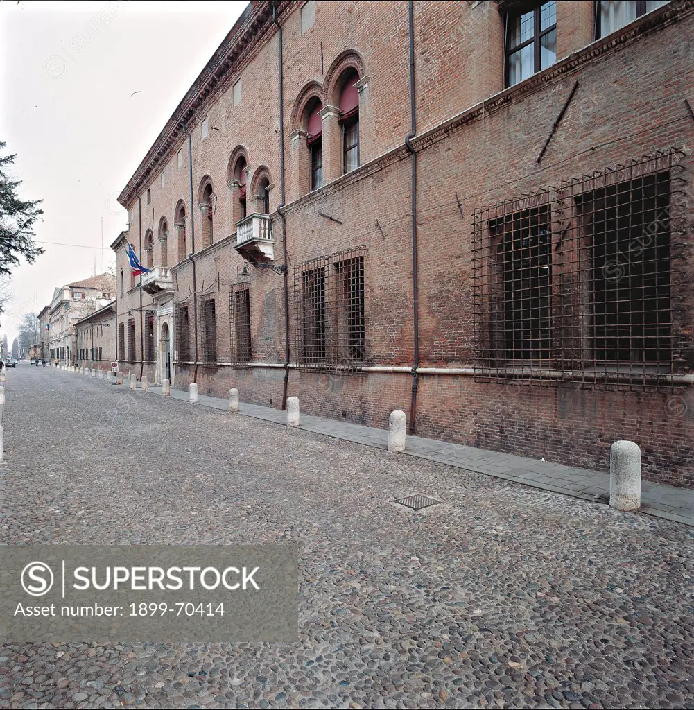 Italy, Emilia-Romagna, Ferarra. The façade presents a duotone scheme of colours: the white marble portal frames and upper balconies and the red brick walls. On the first storey are fine single-lancet windows carved with the moulded terracotta technique.