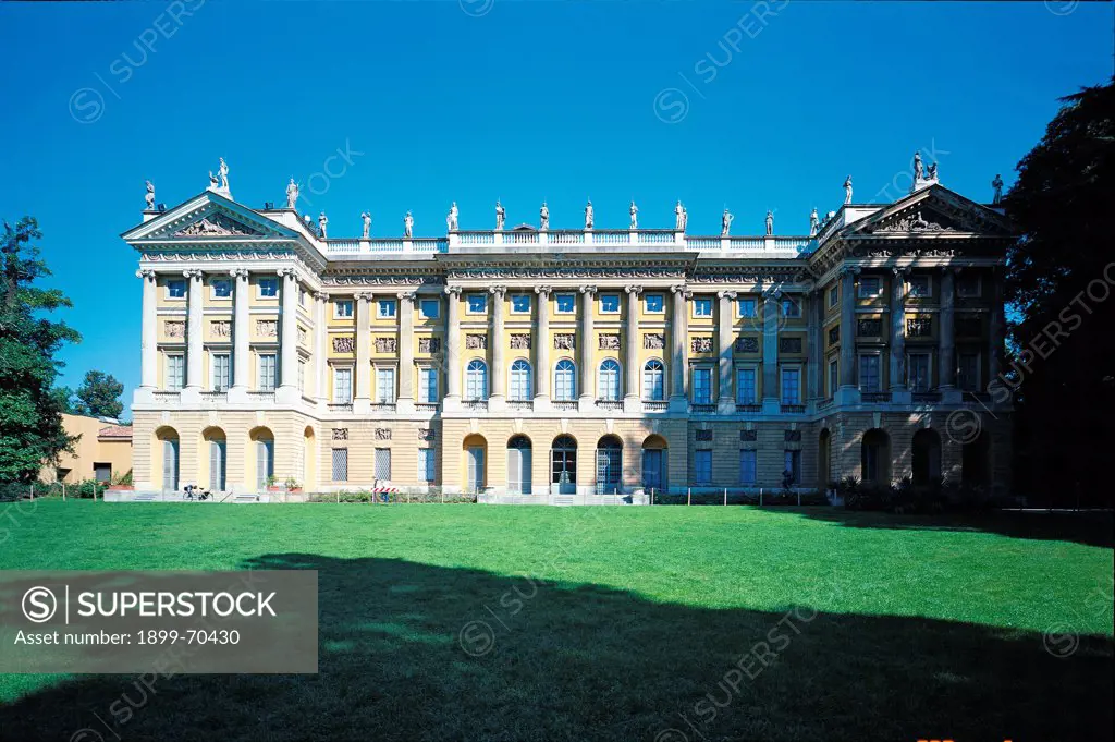 Italy, Lombardy, Milan, Villa Belgiojoso Bonaparte. Whole artwork view. A front view of the palace of the villa that faces a large meadow. The frontage shows balustrades, pilasters, statues, a tympanum contained by cornice, a frieze and reliefs.