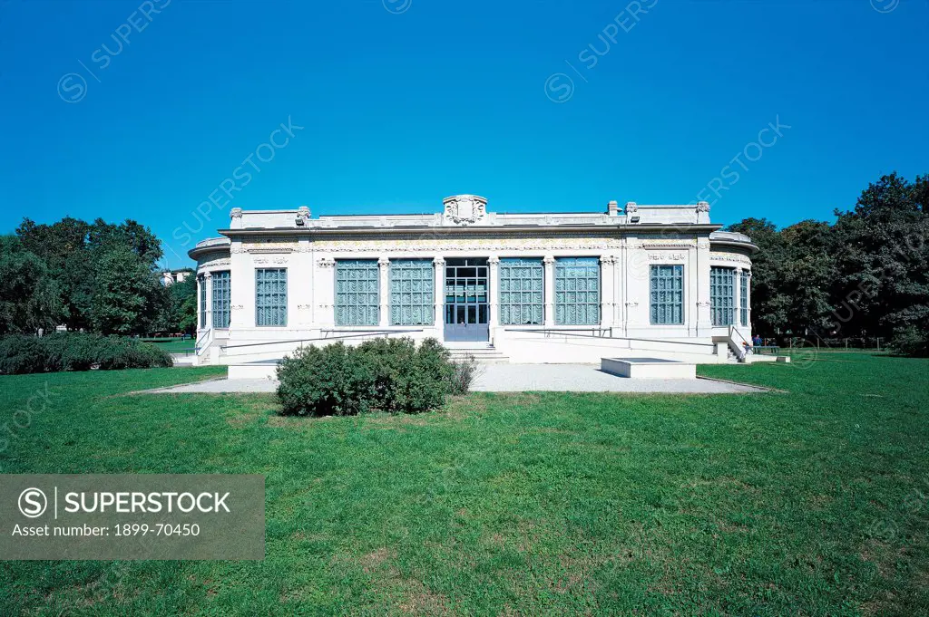 Italy, Lombardy, Milan, Largo Marinai d'Italia 1. Whole artwork view. View of the facade of the building with the entrance. All around a blue sky and a green meadow.