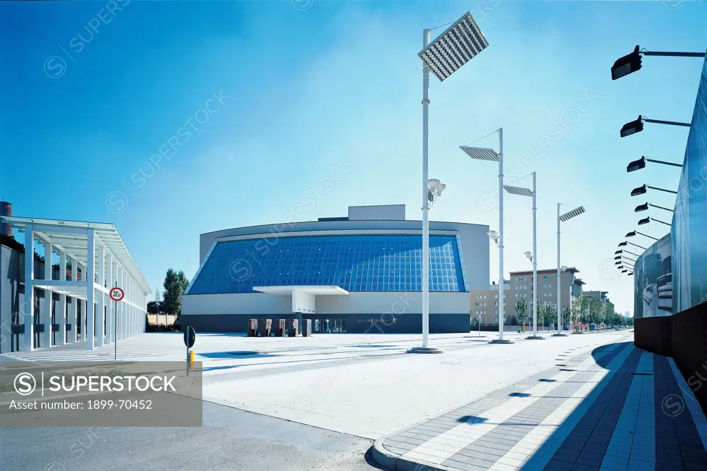 Italy, Lombardy, Milan, via dell'Innovazione 1. Detail. View of a street with streetlamps and the structure of the theatre with arcades, entrance and a big glass wall. The building is in Bicocca district.