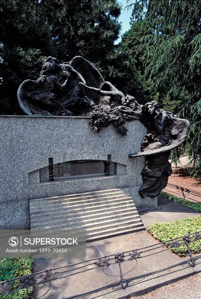 Italy, Lombardy, Milan, Memorial Cemetery. Whole artwork view. Frontal view of the tomb that presents a sculpted group depicting some crying winged angels.