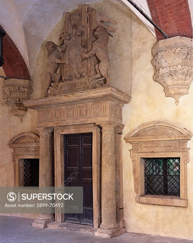 Italy, Emilia-Romagna, Bologna, Palazzo Comunale. Whole artwork view. Foreshortened view of the imposing portal that is composed of two levels: a cornice with columns and pillars supporting a Doric entablature, and a couple of rampant lions that carry the emblem of the city of Bologna.