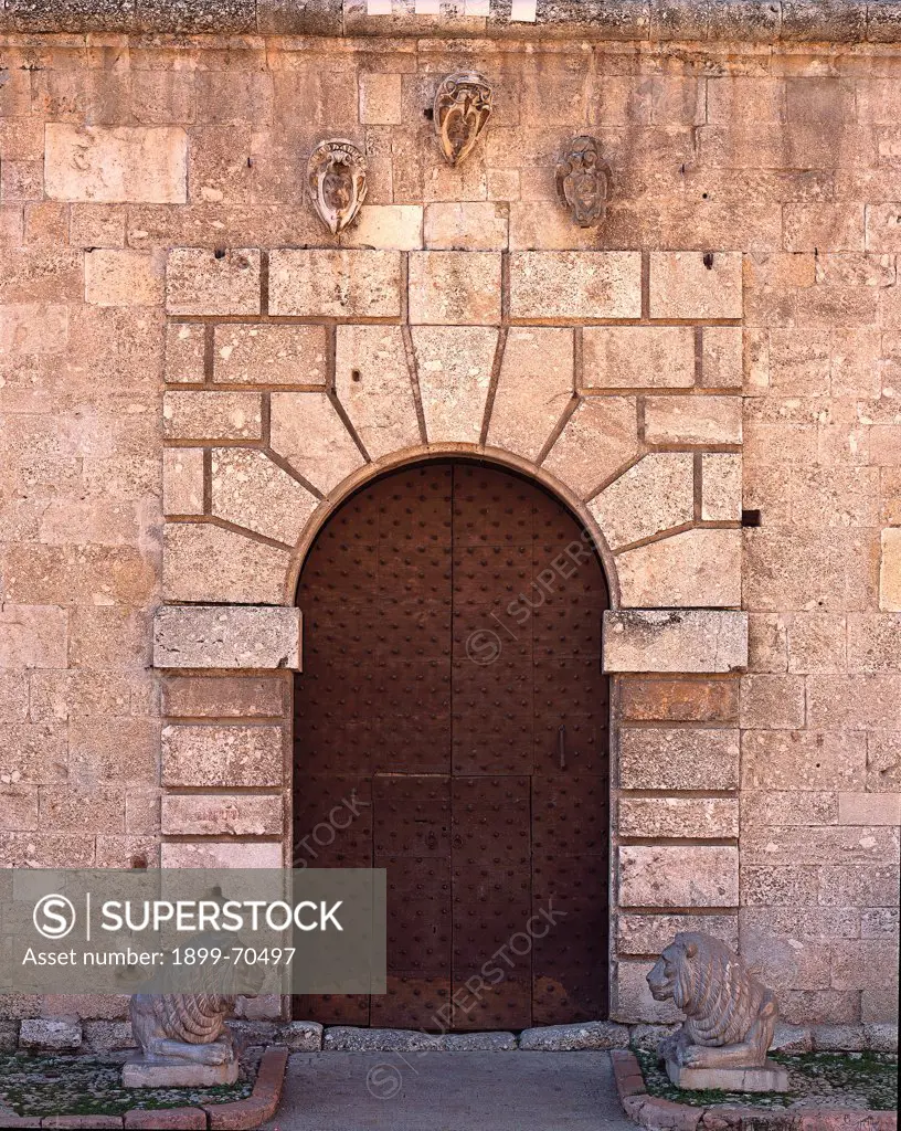 Italy, Umbria, Norcia (Perugia), Museo Civico Diocesano La Castellina. Whole artwork view. Front view of the arch portal that is decorated with flat ashlars, two sculpted lions and surmounted by three coats of arms.